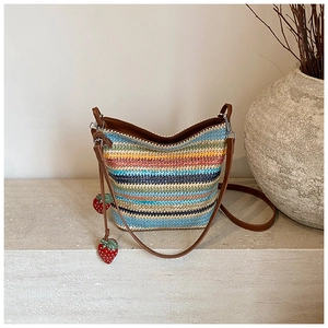 Close-up of rainbow woven straw bag featuring decorative red strawberry charms