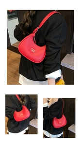 Detail of red crescent hobo bag with lychee grain leather and silver metal logo