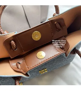 Dettaglio della chiusura magnetica della borsa a secchiello in pelle marrone e denim