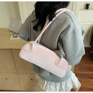 Gros plan d'un sac à bandoulière rectangulaire rose clair porté par un mannequin en intérieur