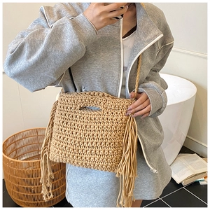 Detail of light khaki woven bag featuring stylish long side tassels and handle