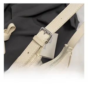 Detail of off-white lychee texture bag with silver buckle and metallic COIN logo