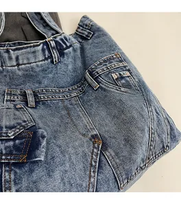 Close-up of blue washed denim bag featuring reinforced stitching and metal zipper detail