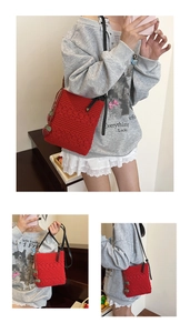 Detail of red crochet woven bag with 3D strawberry charms and black zipper closure