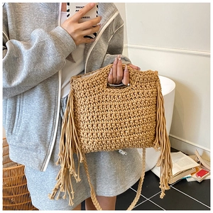 Close-up of bohemian knit crossbody bag featuring long fringes and sturdy braided handle