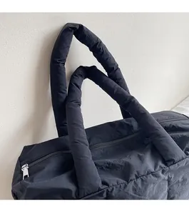 Close-up of padded shoulder strap and quilted texture on black puffer tote bag