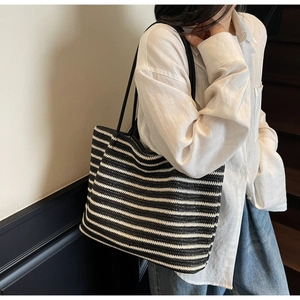 Close-up of a large black and white striped woven tote bag with slim shoulder straps