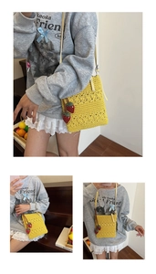 Detail of yellow crochet crossbody bag with 3D strawberry charms and floral texture