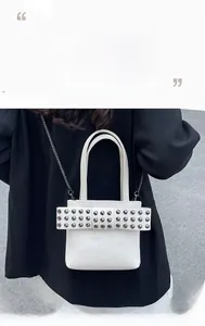 Détail du sac en cuir blanc avec nœud orné de rivets et bandoulière en chaîne métal