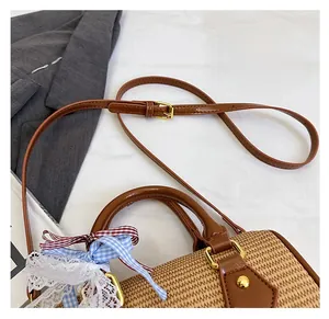 Détail du sac à main en paille tressée avec lanières en cuir brun et rubans en tissu