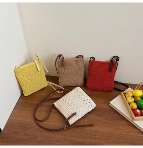 Detail showing various colors of handmade crochet strawberry bags on a wooden floor