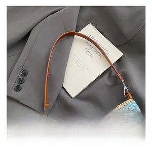 Close-up of rainbow woven bucket bag with brown leather handle and metal buckle details