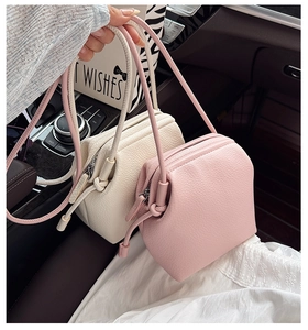 Close-up of minimalist crossbody bags in pink and beige with lychee grain leather texture