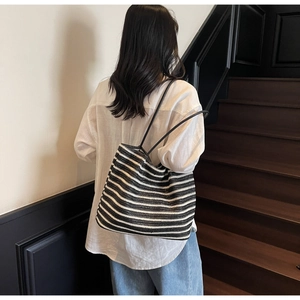 Detail of striped woven straw tote bag showing large capacity on a female model