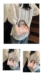 Dettaglio borsa in pelle rosa con manici marroni e finiture del logo in metallo dorato