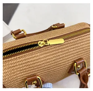 Gros plan sur la fermeture éclair dorée et la texture tissée du sac Boston