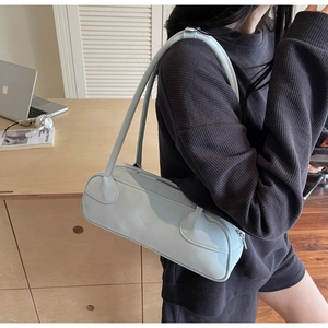 Detail of light blue minimalist baguette bag showing long shoulder strap and matte leather texture