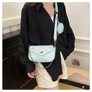 Close-up of light blue quilted crossbody bag with gold chain and round coin purse detail