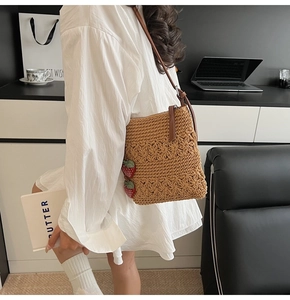 Detailed close-up of brown crochet woven shoulder bag with red strawberry charms