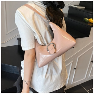 Detail view of pink patent leather shoulder bag with a silver circular metal buckle