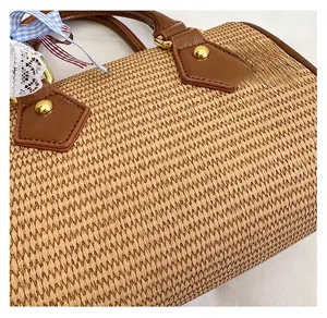 Détail du sac en paille tressée avec poignée en cuir marron et ruban à carreaux bleus