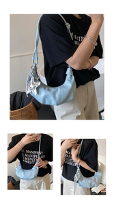 Close-up of a light blue crescent shoulder bag featuring glossy finish and star pendant