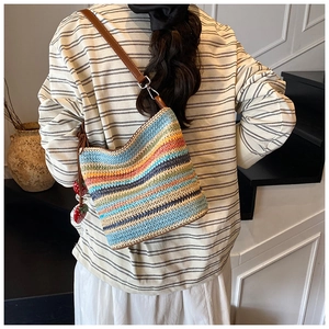 Detail of colorful woven shoulder bag featuring strawberry charms and leather strap