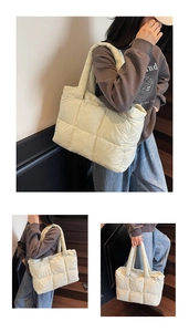 Close-up of cream quilted puffer tote bag with wide shoulder strap and soft padding