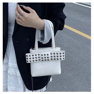 Détail du sac à main en cuir litchi blanc avec un grand nœud et des rivets métalliques