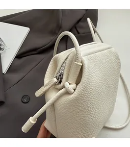 Close-up of creamy white lychee grain leather shell bag with smooth zipper detail