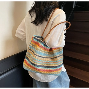 Detailed view of a colorful striped woven straw tote bag with brown leather handles