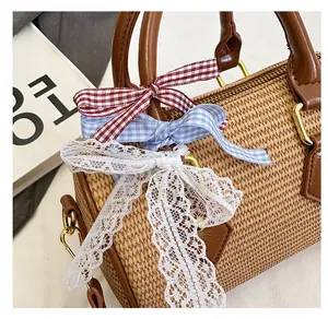 Détail de nœuds décoratifs en dentelle et à carreaux sur la poignée d'un sac