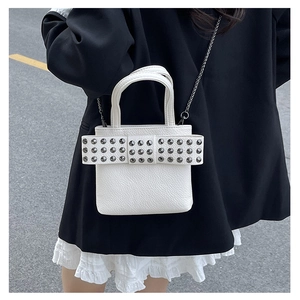Detail of white studded bow on lychee texture mini bag with dark metal chain strap