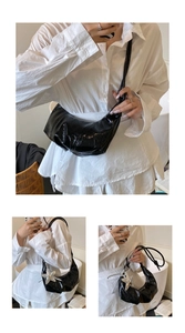 Detail of black glossy crescent bag with a silver star charm and pleated leather finish