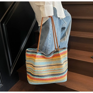 Close-up of vibrant rainbow woven tote bag with durable brown leather handle and texture