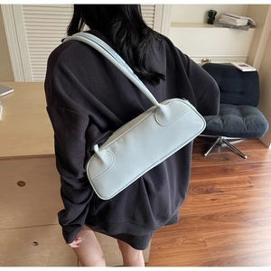 Détail du sac baguette bleu clair montrant la texture du cuir mat sur l'épaule du mannequin