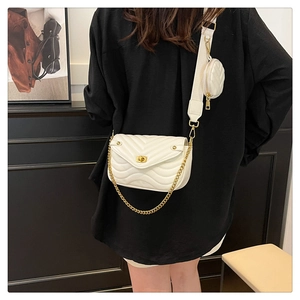 Detail of white quilted crossbody bag with golden chain and small round coin purse attachment