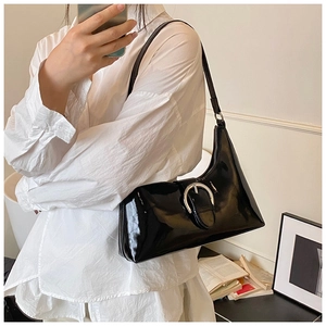 Close-up of black patent leather underarm bag with silver metal buckle on a shoulder strap