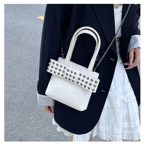 Détail du sac à main blanc orné d'un grand nœud à rivets argentés et bandoulière chaîne