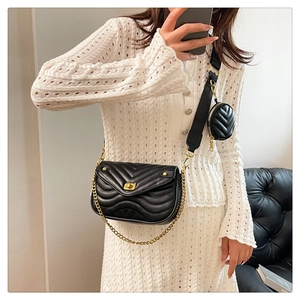 Detail of black quilted leather shoulder bag with gold chain and round coin purse accessory