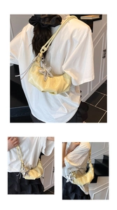 Detail of pale yellow patent leather half-moon bag with silver starfish charm accent