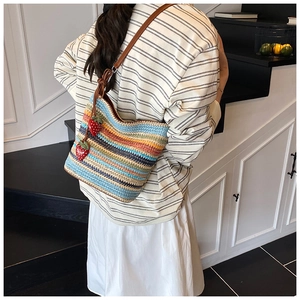 Detail of colorful striped woven bucket bag with leather strap and strawberry charms