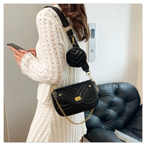 Side view of black V-quilted crossbody bag with a round coin pouch and gold chain