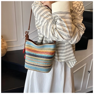Detail of colorful striped woven bucket bag with leather strap and red tassel charm