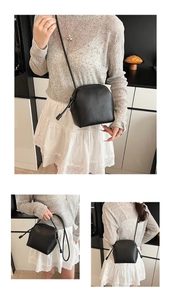 Detail of black lychee grain leather shell bag showing drawstring knot strap design