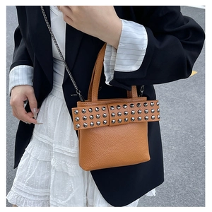 Détail du sac à main en cuir caramel avec rivets argentés et bandoulière en chaîne