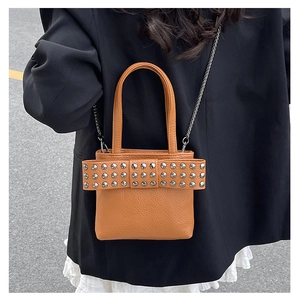 Brown litchi leather handbag featuring a large bow and silver rivet studs detail