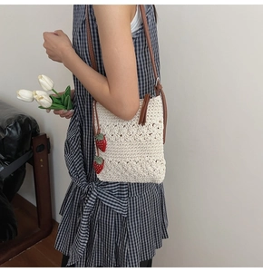 Detail der handgewebten Häkeltasche in Creme mit Erdbeeranhängern und braunem Gurt