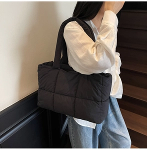 Side view of black quilted puffer tote bag featuring wide straps and spacious nylon design