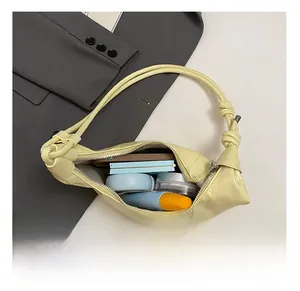 Interior capacity detail of yellow dumpling bag showing phone and cosmetics on grey blazer